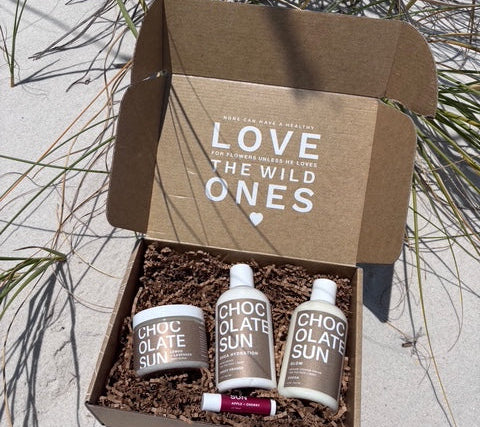 Box of 'Love the Wild Ones' products on a sandy surface with grass.